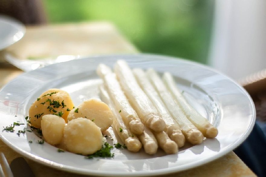 Asparagus with potatoes served on a plate to the table