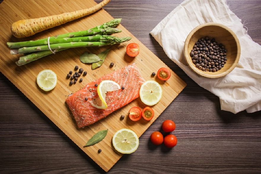 Salmon file on a board decorated with asparagus